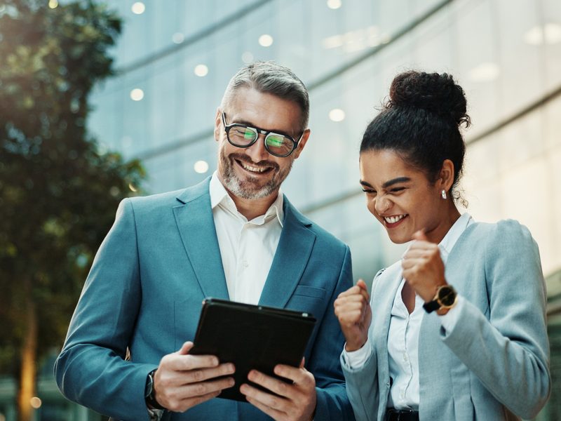 Imprenditore e responsabile finance sorridenti consultano su tablet il recupero crediti automatizzato 1.2.3. Pagato di Kollego®